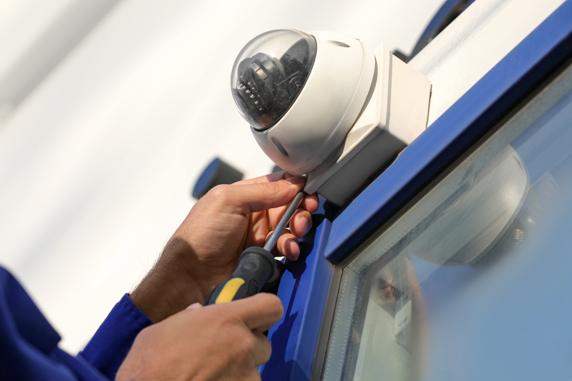 Technician installing CCTV camera on wall outdoors, closeup